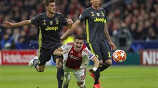 Záloník Ajaxu Duan Tadi se ítí k zemi, zatímco Daniele Rugani a Mario...