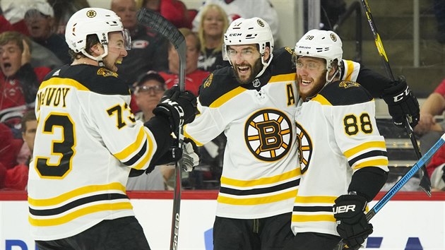 David Pastrk, Patrice Bergeron a Charlie McAvoy (zprava) slav branku na led Caroliny.