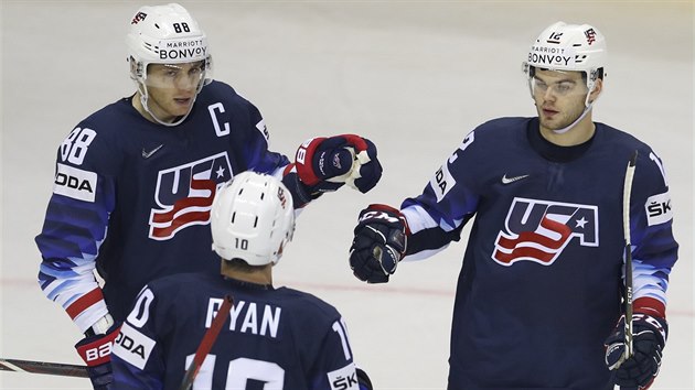 Amerian Alex Debrincat (vpravo), kapitn Patrick Kane (vlevo a Derek Ryan si ukaj na znamen uznn.