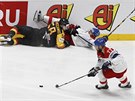 Český útočník Milan Gulaš bere puk před ležícími hokejisty na ledě.