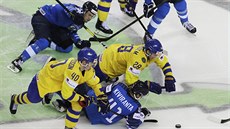 BITVA O PUK. védtí a fintí hokejisté po vhazování svádí tuhý boj o puk.