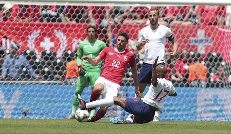 Anglický fotbalista  Fabian Delph se pokouí zastavit skluzem výcara Fabiana...