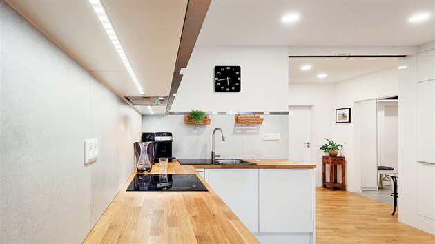 Podsvícení v celé délce horních skříněk kuchyňské linky je nejen efektní, ale především praktické. V pozadí je otevřený a prosvětlený střed bytu.