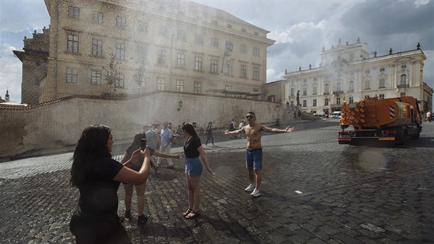 Turisté i Pražané se chladí díky kropícímu vozu na Hradčanském náměstí v Praze (15. 6. 2019).