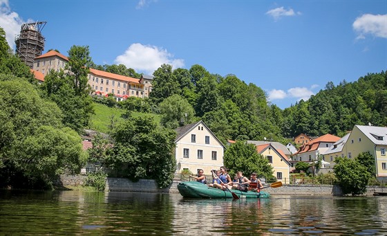 V Rožmberku nad Vltavou plují vodáci pod hradem, který se tyčí nad řekou. Je...