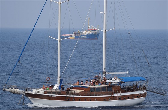 Turisté na jacht pozorují lo Sea Watch 3, která je naloená benci z Afriky,...