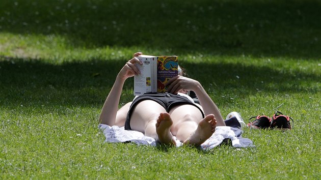 Čtenářka si užívá vedra na trávě v severofrancouzském Lille. (24. 6. 2019)