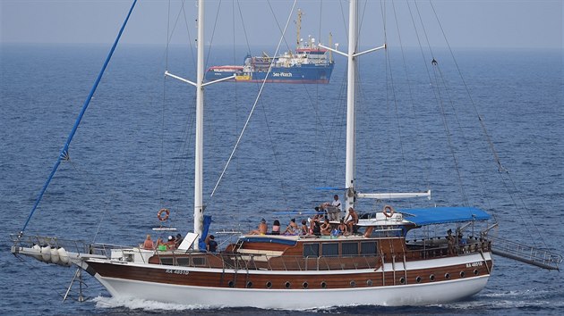 Turisté na jachtě pozorují loď Sea Watch 3, která je naložená běženci z Afriky, čekajícími na vylodění na italském ostrově Lampedusa. (28. června 2019)