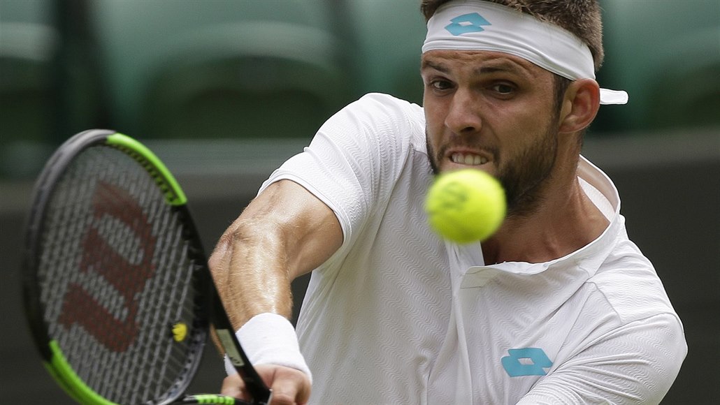 Ji�í Veselý hraje bekhend ve Wimbledonu. 