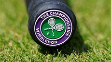 Rukoje tenisové rakety s logem na tráv ve Wimbledonu.