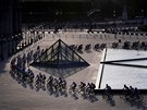 TRADINÍ ZÁVR. Peloton cyklist projídí nádvoím muzea Louvre v Paíi bhem...