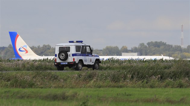 Rusk policejn auto u letadla, kter nouzov pistlo v kukuinm poli u Moskvy (15. 8. 2019)