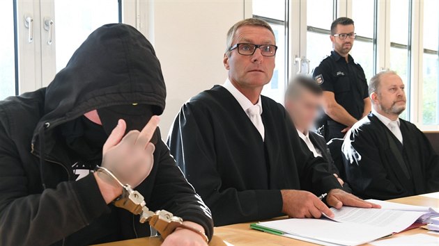 Devatenctilet pachatel (vlevo), kter se u soudu piznal k vrad mlad eny, ukazuje prostednek na novine. Vpravo s rozmazanou tv je 21let spolupachatel. (20. srpna 2019)