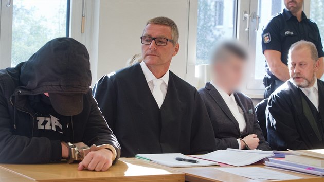 Devatenctilet obvinn z vrady (vlevo v kpi) a 21let obvinn (vpravo s rozostenm obliejem) u soudu. (20. srpna 2019)