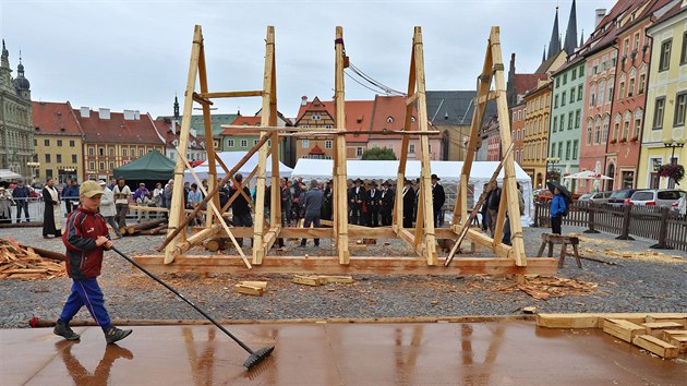 Tesaři na náměstí v Chebu sestavují a vztyčují pomocí bidla a kladkostroje zmenšenou repliku nejstaršího českého krovu.