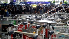 Protestující prochází za barikádami, které jsou na čínském mezinárodním letišti...