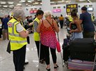 Zamstnanci britského úadu pro civilní letectví pomáhají cestujícím na letiti...