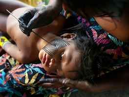 TVÁŘ JAKO PLÁTNO. Žena z domorodého kmene Kayapů kreslí své dceři na tvář...