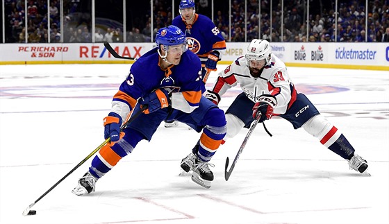 Mathew Barzal z NY Islanders u puku, brání ho Radko Gudas z Washingtonu.