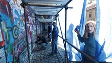Lidé u Lennonovy zdi zvdav nahlíí za plachtu, kde zaala její oprava (7. 10....