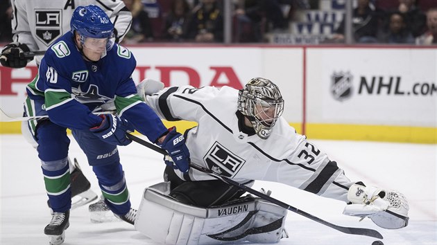 Jonathan Quick v brance Los Angeles se natahuje po puku, kter chce ukoistit Elias Pettersson z Vancouveru.