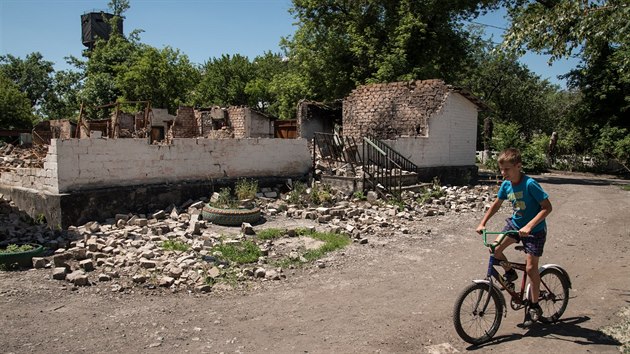 Chlapec projd na kole kolem znien budovy v donck vesnici Novotoshkivske. (8. ervna 2015)