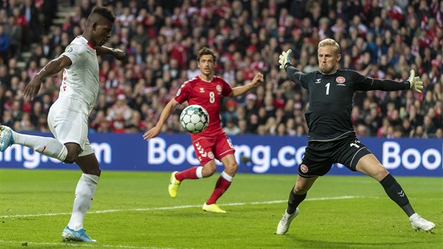 Dánský brankář Kasper Schmeichel (vpravo) likviduje šanci Breela Embola ze Švýcarska v kvalifikaci na Euro 2020.