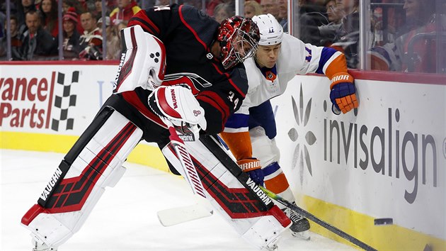Brank Caroliny Petr Mrzek vyhazuje puk, napad ho Matt Martin z New York Islanders.