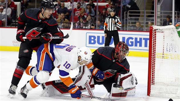 Brank Caroliny Petr Mrzek schovv puk ve sv rukavici, Derick Brassard z New York Islanders pijel pozd.