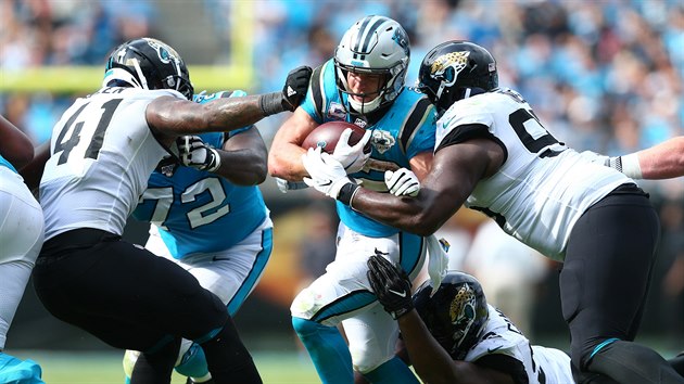 Christian McCaffrey (v modrm) z Carolina Panthers se tla mezi obrnci Jacksonville Jaguars.