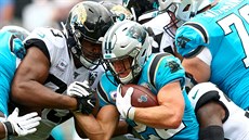 Christian McCaffrey (v modrém) z Carolina Panthers se tlaí mezi obránci...