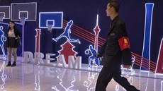 len ochranky prochází kolem neonové expozice v Pekingu vnované basketbalu.