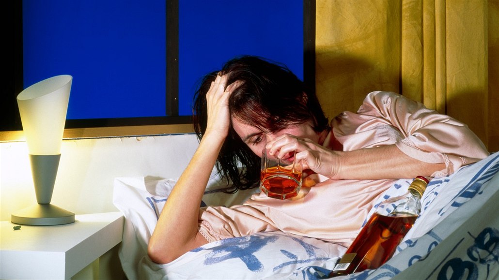 Žena pije alkohol v posteli