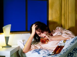 Žena pije alkohol v posteli