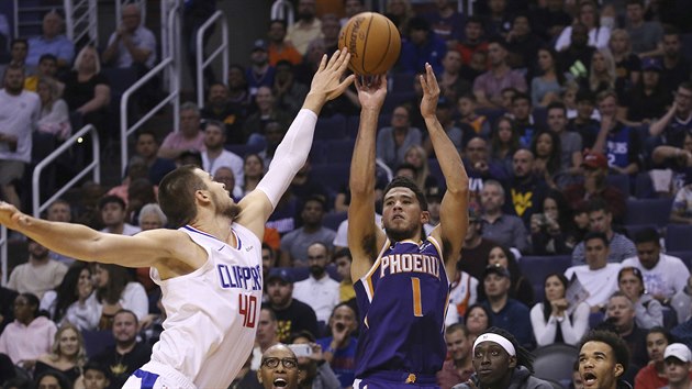 Devin Booker z Phoenixu pi stelb, brn ho Ivica Zubac z L.A. Clippers.