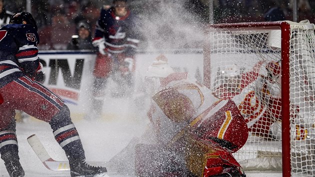 Brank David Rittich z Calgary pod ledovou sprchou v zpase pod irm nebem proti Winnipegu.