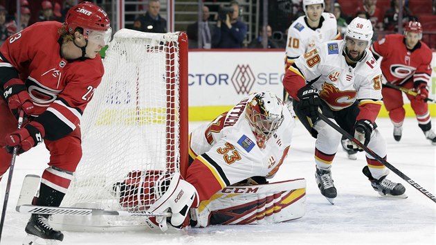 Brock McGinn z Caroliny vlevo zkou pekvapit Davida Ritticha v brannce Calgary. Brn i vdsk bek Oliver Kylington (58).