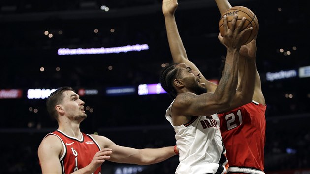 Kawhi Leonard (v blm) z LA Clippers se tla na ko Portlandu kolem Hassana Whitesidea (vpravo), sleduje je Mario Hezonja.