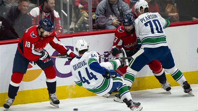 esk obrnce v dresu Washingtonu Radko Gudas (druh zprava) bojuje u mantinelu s protihri z Vancouveru.