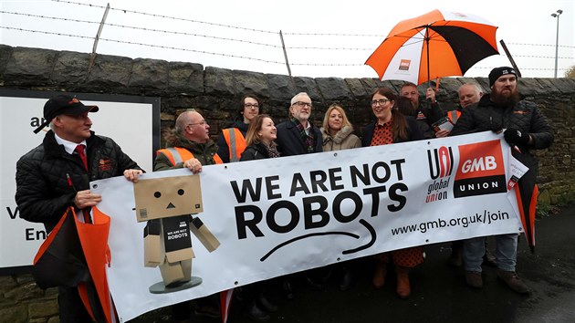 „Nejsme roboti,“ hlásá transparent, který v rukou drží zaměstnanci Amazonu v britském Sheffieldu. Podpořit je přišel i Šéf Labouristické strany Jeremy Corbyn. (23. listopadu 2019)