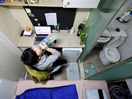 Kim Jae-hoon drinks water as he sits in his cubicle, called a goshi-won, where...