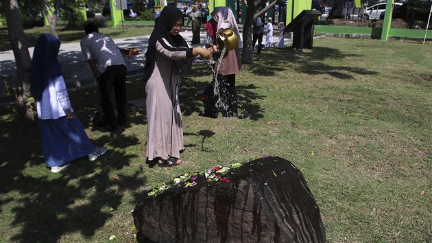 V Indonsii si pi pleitosti patnctho vro pipomnaj obti niiv vlny tsunami z roku 2004. ena na snmku polv vodou kmen na masovm hrob ve mst Banda Aceh na Sumate. (26. prosince 2019)