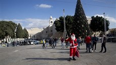 Palestinec v kostýmu Santa Klause vítá křesťanské návštěvníky před kostelem...