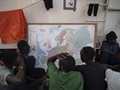 Zachránní migranti se na palub humanitární lodi Ocean Viking dívají na mapu...
