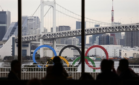 Lidé sledují obří olympijské kruhy v Tokiu.