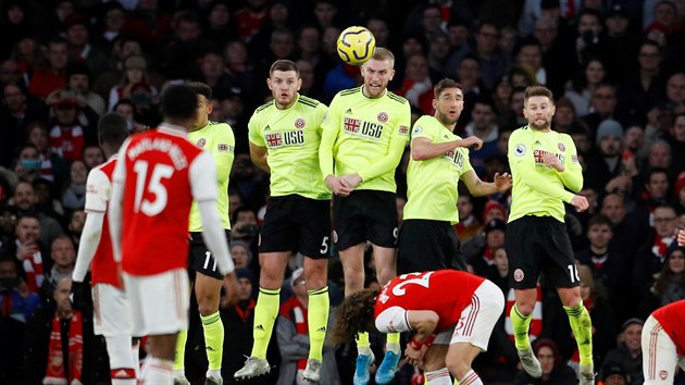 Oliver McBurnie (uprosted) z tmu Sheffield United zasahuje proti balonu v utkn s Arsenalem.