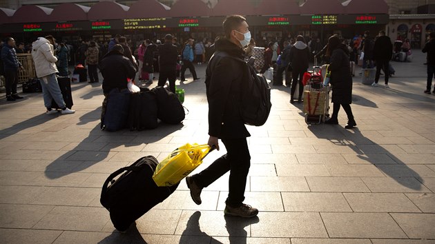 Muž se chrání respirační rouškou u nádraží v Pekingu. Nová forma koronaviru se z města Wu-chan rozšířila za hranice Číny. (17. ledna 2020)