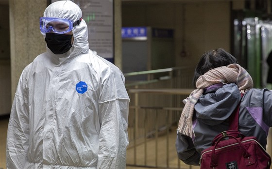 Cestující v pekingském metru prochází kolem pracovníka v ochranném obleku. (24....