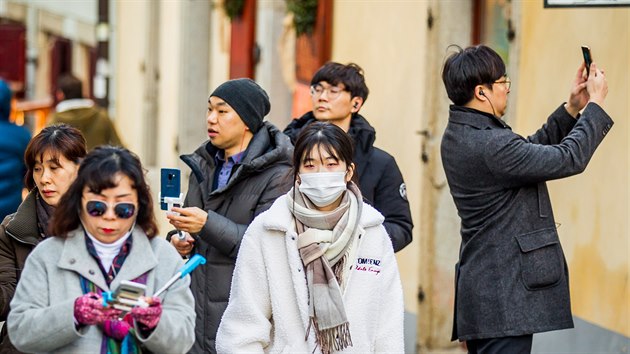 Nkte turist z Asie si pi prohldce eskho Krumlova chrn obliej roukou. (17. jna 2019)