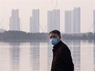 Muž s maskou na břehu řeky v čínském městě Wu-chan, které je epicentrem nákazy...